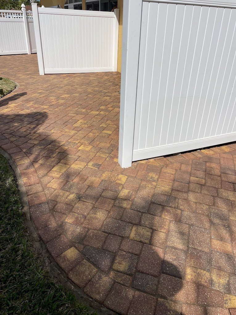 Clean white vinyl fence and freshly sealed paver walkway after professional exterior cleaning by Suncoast Softwash in Brevard County, FL.